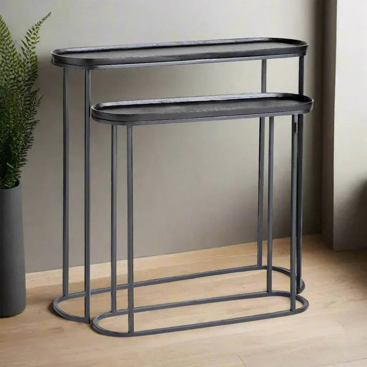 Black metal nesting console tables set of 2 styled against wall with tray tops and slim open frame design for modern interiors