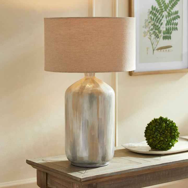 Neutral coastal table lamp with hand-painted iron base and linen shade styled on wood console with natural decor.

