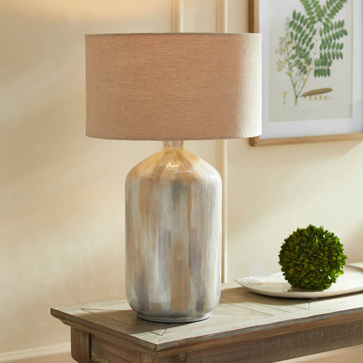 Neutral coastal table lamp with hand-painted iron base and linen shade styled on wood console with natural decor.

