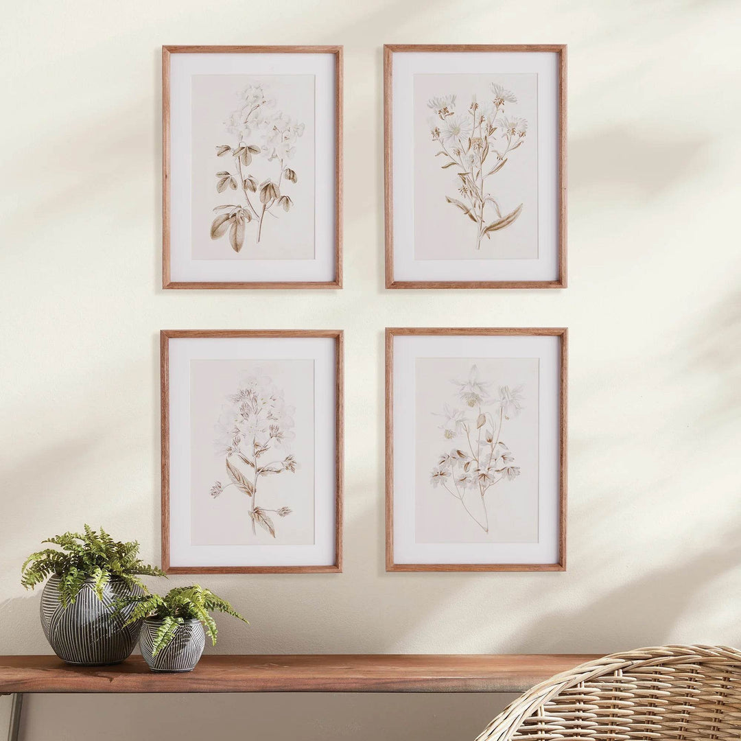 Botanical print wall decor with natural wood frames styled above a wooden console table in soft natural lighting.
