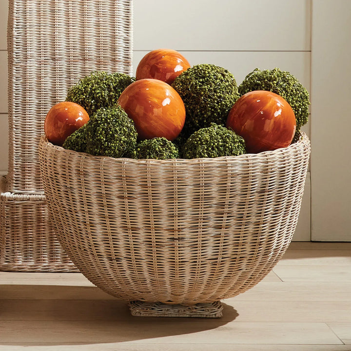 Large orange decorative orb styled in woven bowl with green moss spheres for console decor Coastal Eclectic style