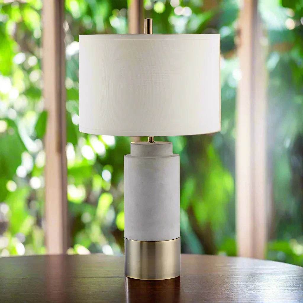 Organic modern table lamp with concrete cylinder base and white shade in bright natural light setting
