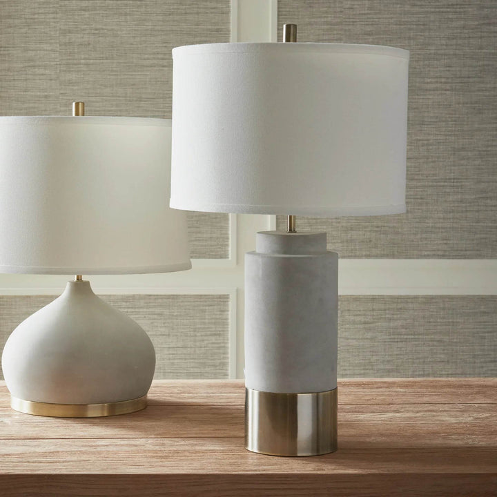 Organic modern concrete and brass table lamp styled on wood console in a neutral interior