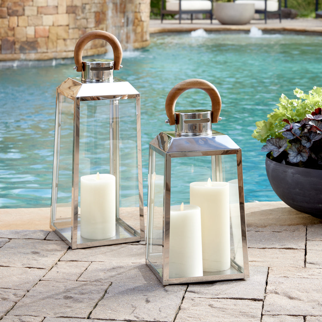 Small and large outdoor stainless steel lanterns with teak wood handles styled poolside with candles coastal lantern