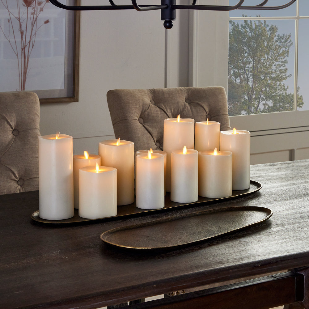 Decorative aluminum trays styled with pillar candles – antique brass oval trays on dark wood table.