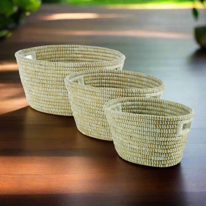 Oval-shaped woven basket set styled indoors on wood flooring, showcasing modern organic floor storage.