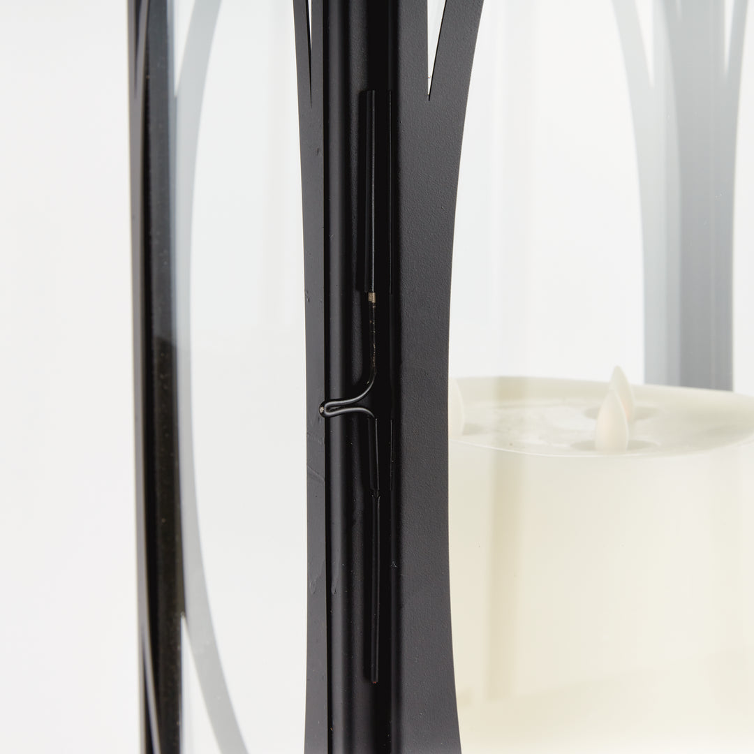 Close-up detail of black oval frame candle lantern with glass panels and metal framework for transitional décor lantern