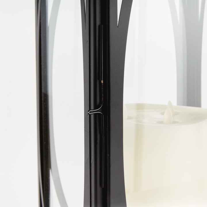 Close-up detail of black oval frame candle lantern with glass panels and metal framework for transitional décor lantern