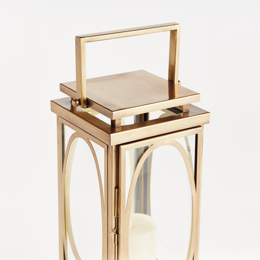 Small brass oval frame candle lantern shown in angled view with glass panels for transitional interior décor lantern