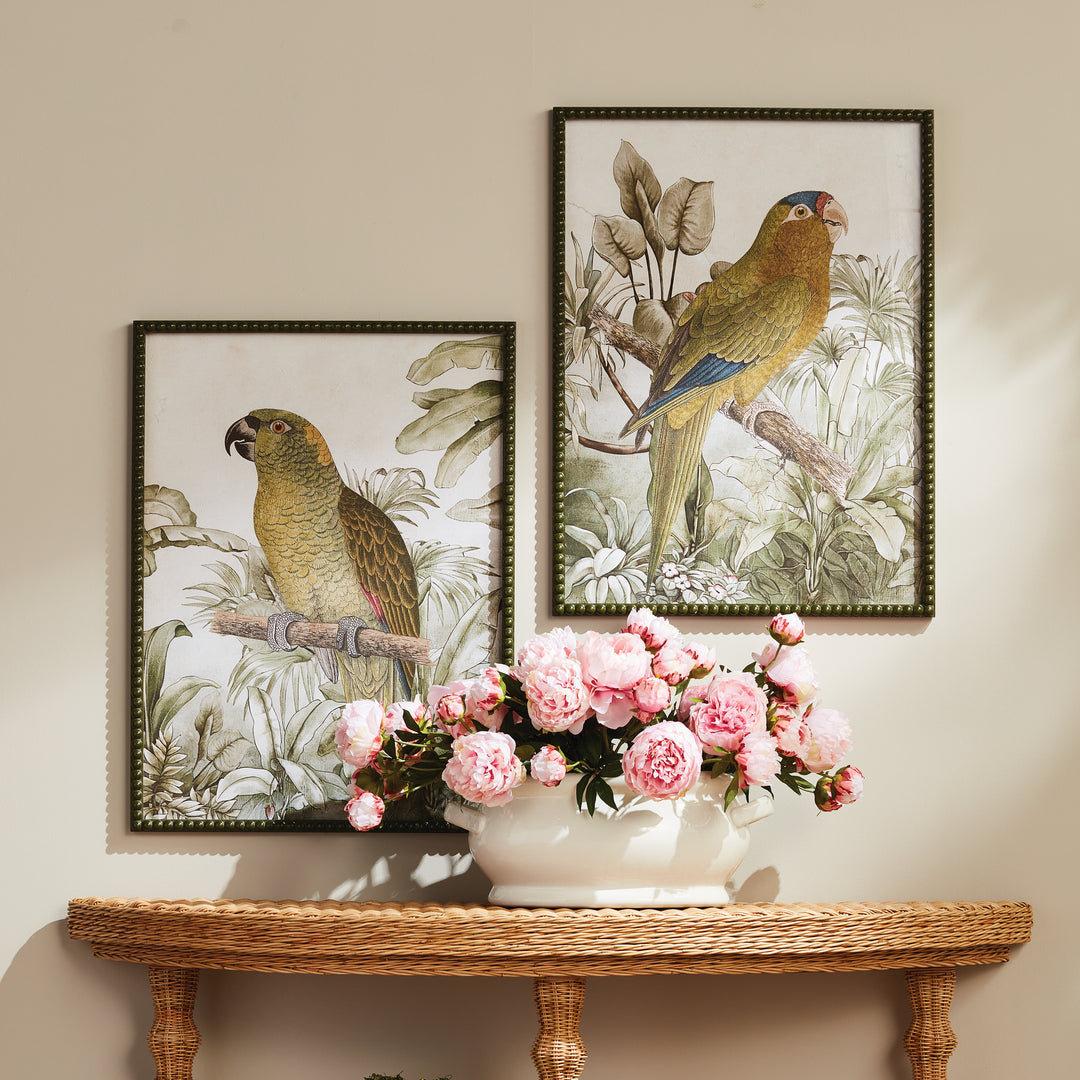 Tropical parrot prints displayed above a wood console with pink floral arrangement, in olive green beaded frames. Traditional