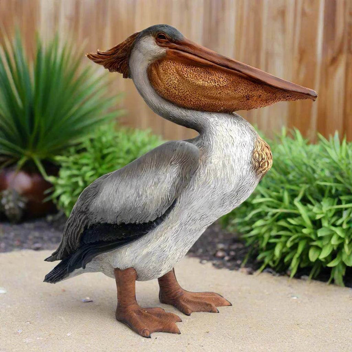 Outdoor pelican garden ornament with antiqued finish styled on patio with desert foliage