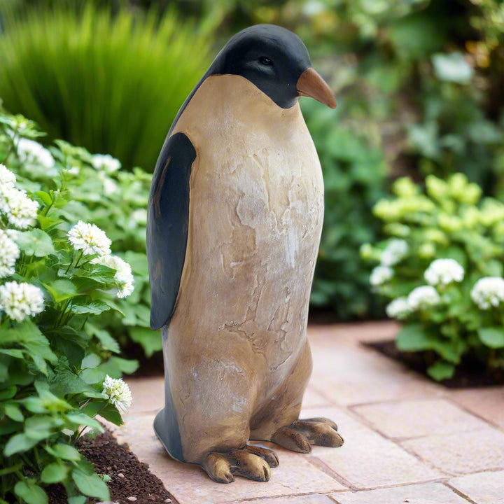 Penguin Outdoor Statue on Brick Garden Path Surrounded by White Flowers and Green Foliage