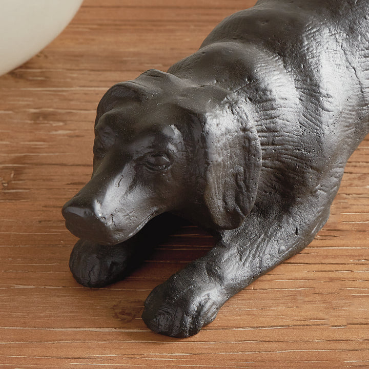 Close-up of playful dog sculpture highlighting facial detail and textured black aluminum finish with bronze undertones.
