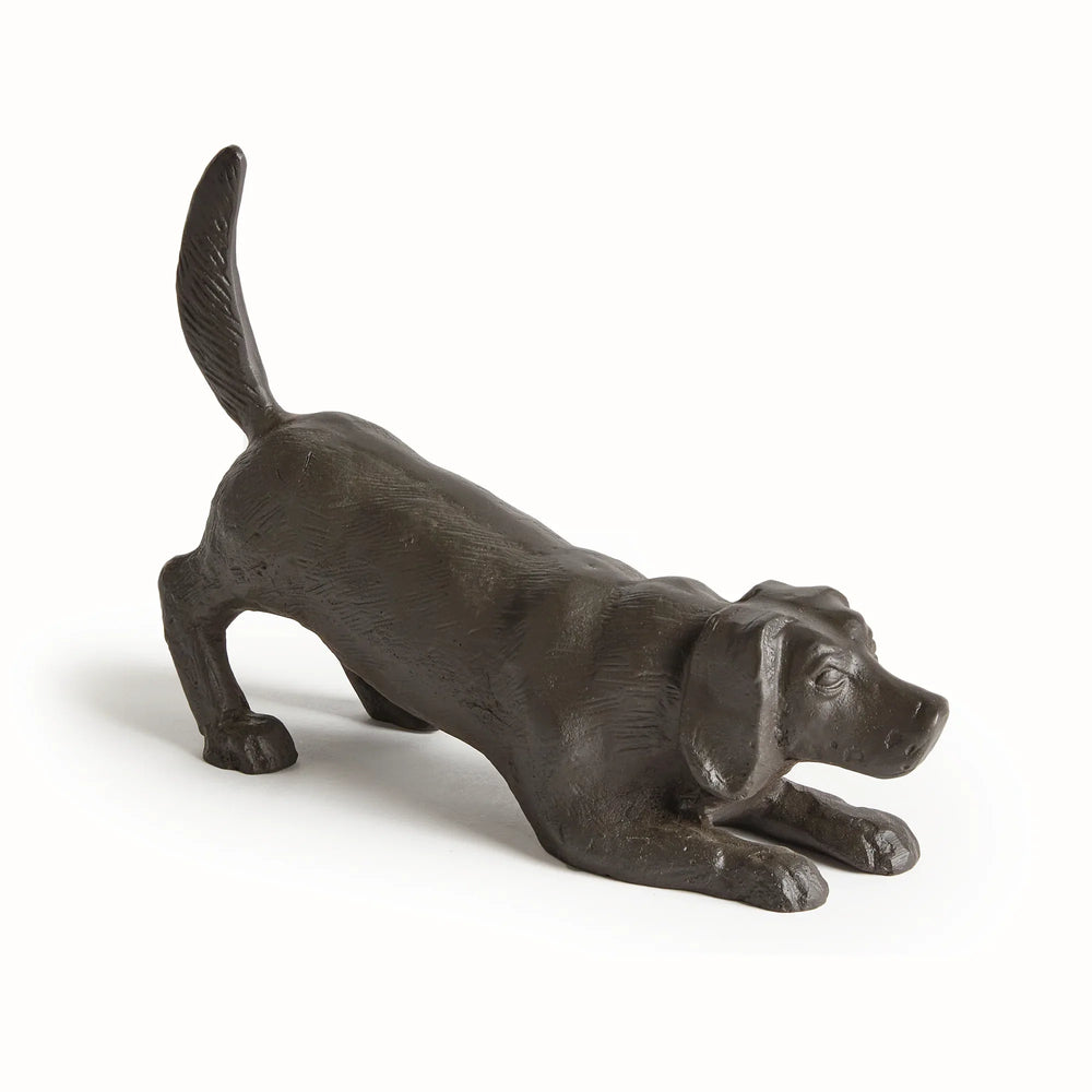 Black playful dog sculpture showing elongated profile and raised tail in cast aluminum with subtle bronze detailing.