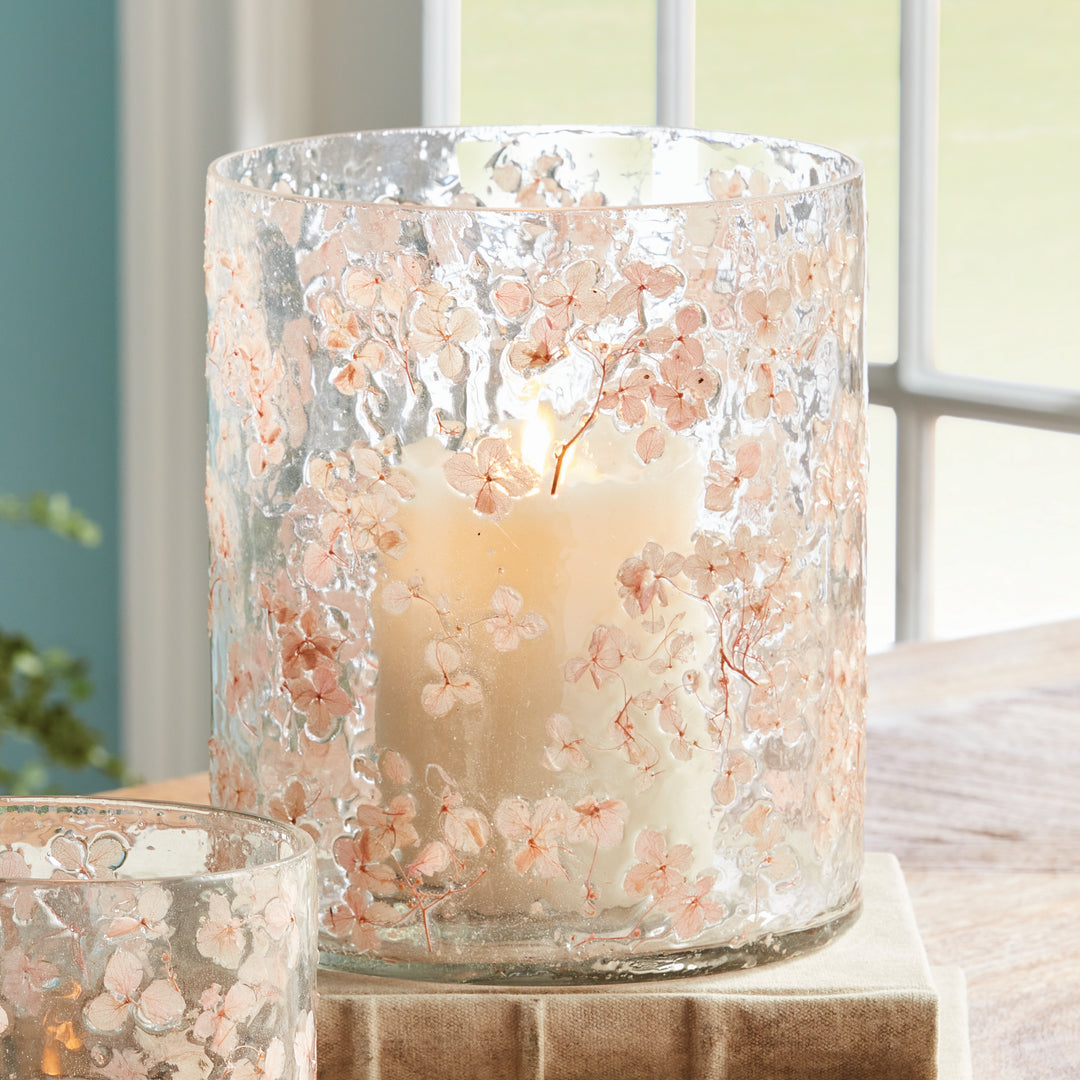 Large clear pink glass hurricane candle holder styled on tabletop with preserved petals and candle glow, Romantic Transitional
