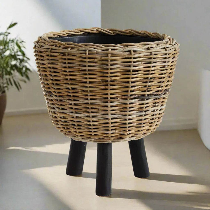 Large rattan planter with legs in natural weave, styled in sunlight for boho-inspired interior settings