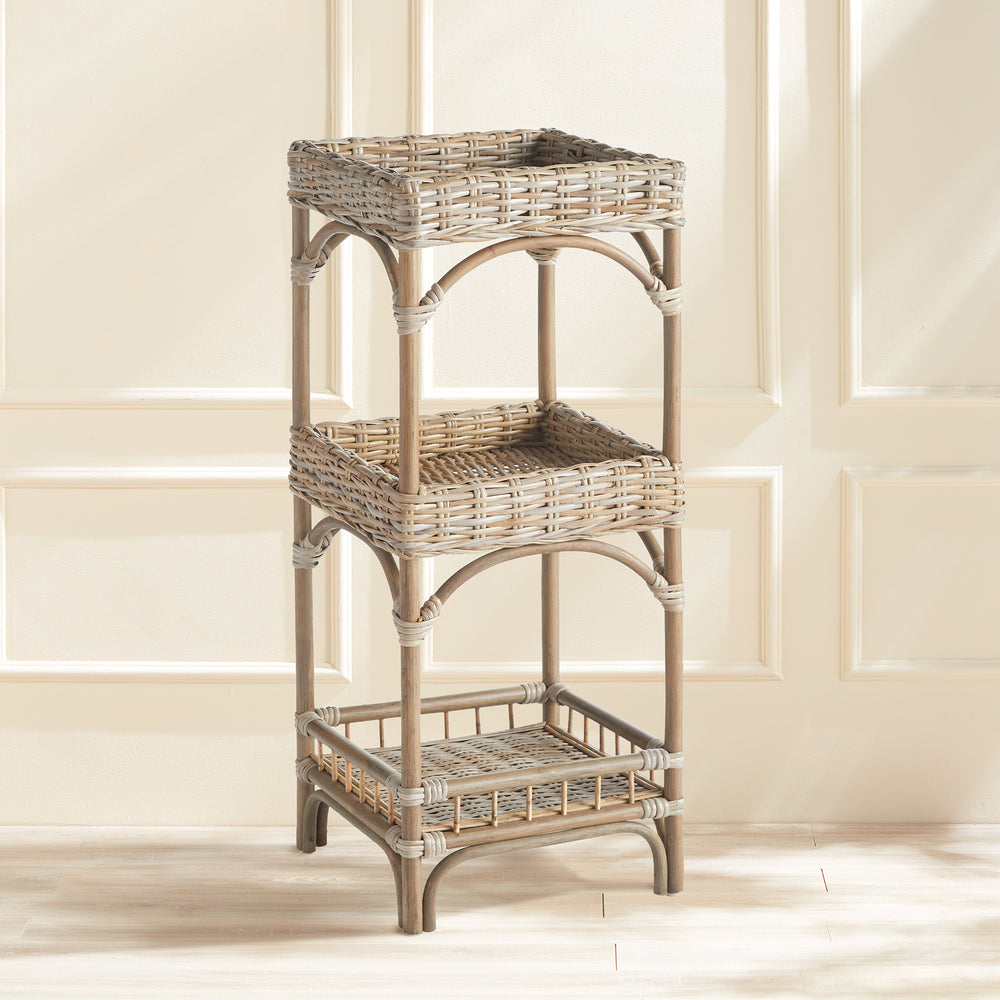 Woven rattan tiered shelf styled in a neutral room with paneling, showing its coastal boho utility.