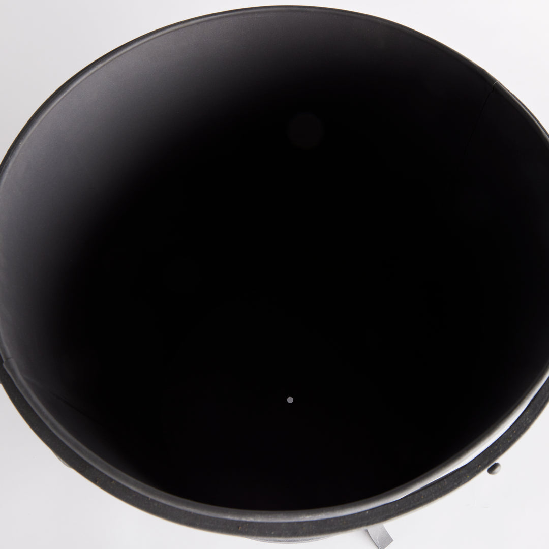Large iron planter viewed from above, showing the dark inner liner and drainage opening at its base. Industrial Transitional