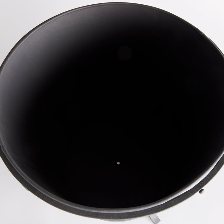 Large iron planter viewed from above, showing the dark inner liner and drainage opening at its base. Industrial Transitional