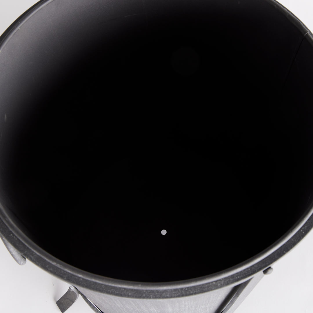 Medium iron planter viewed from above, showing the dark inner liner and drainage opening at its base. Industrial Transitional