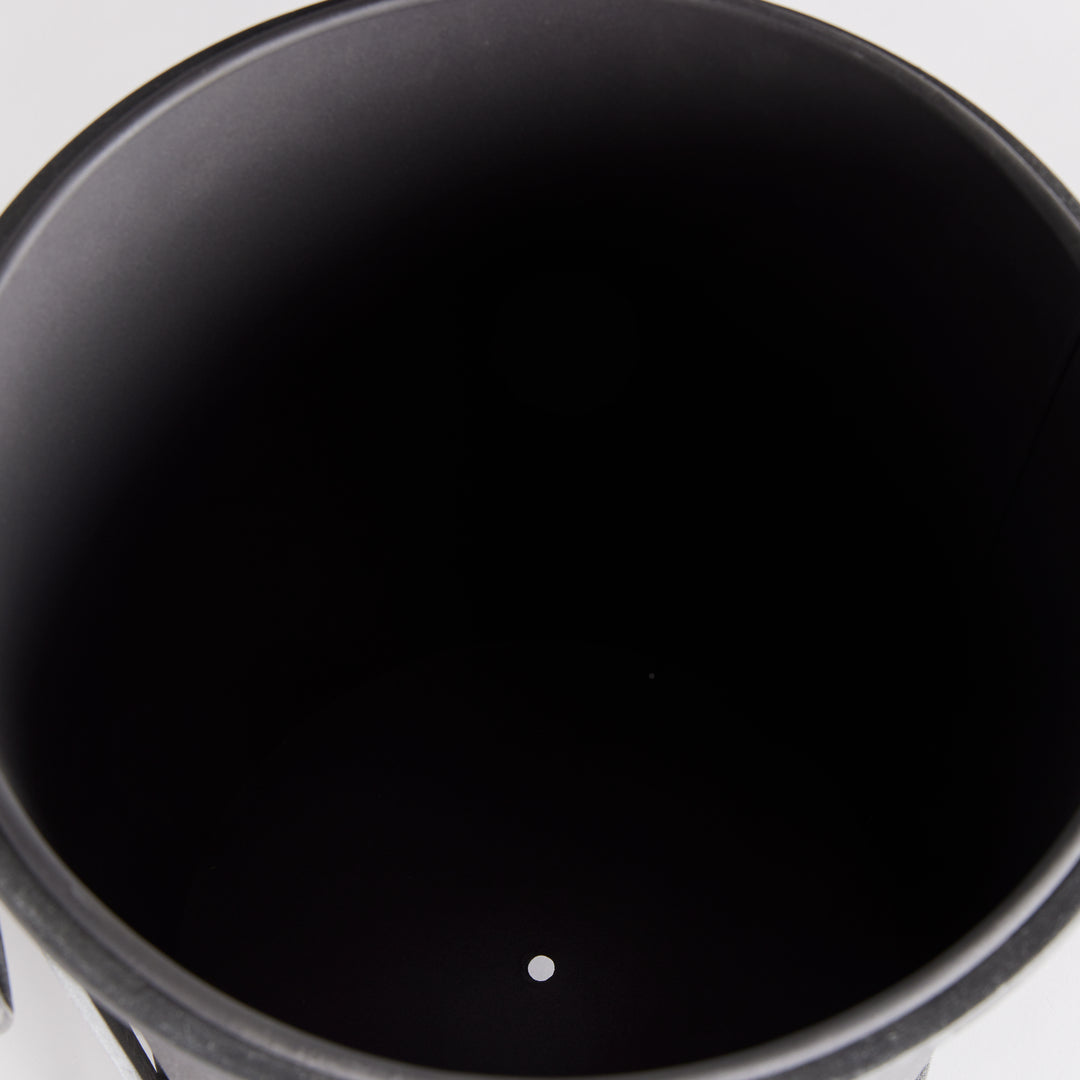 Small iron planter viewed from above, showing the dark inner liner and drainage opening at its base. Industrial Transitional