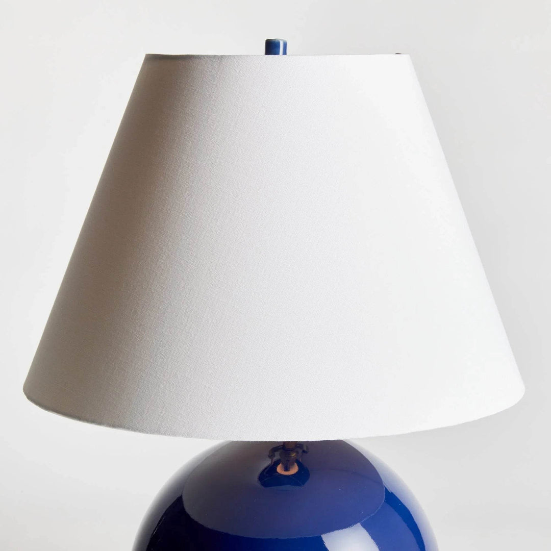 Detail of the white linen empire shade above the rounded blue glazed ceramic base, showing the tapered profile. Transitional