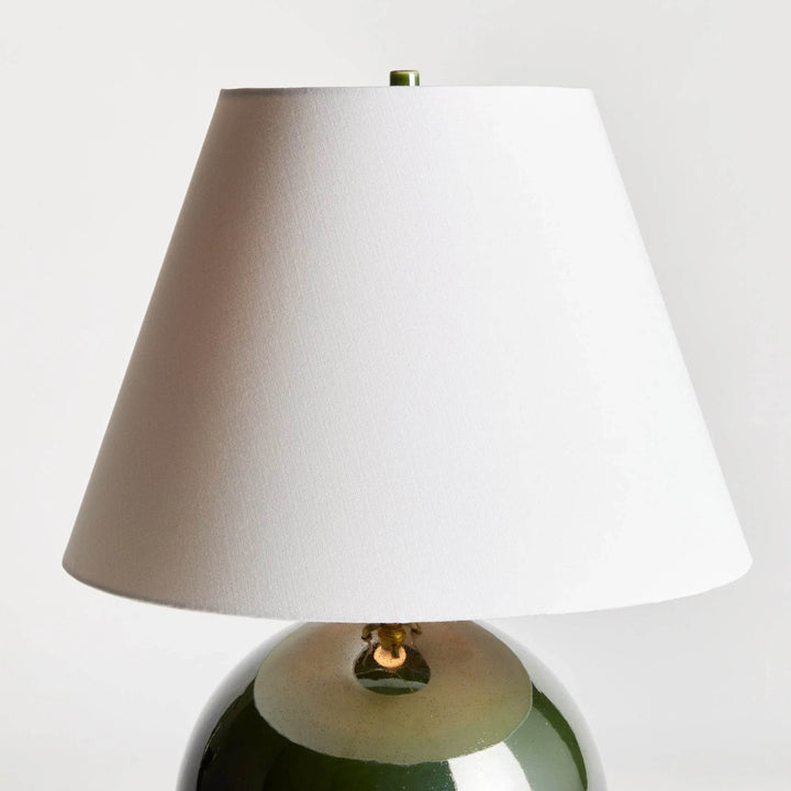 Detail of the white linen empire shade above the rounded green glazed ceramic base, showing the tapered profile. Transitional
