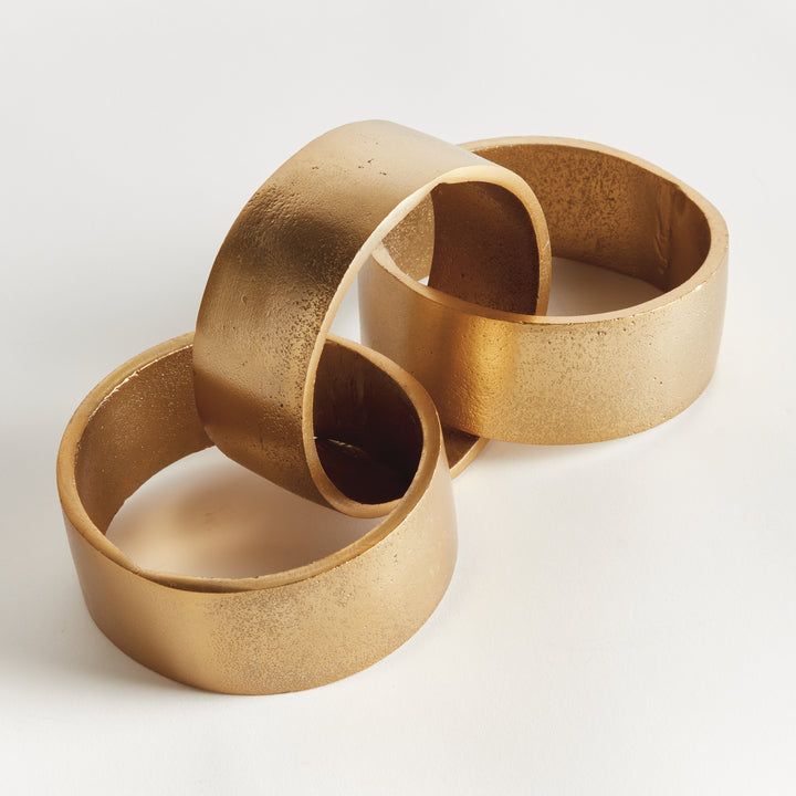 Angled view of gold chain-link sculpture with three cast aluminum links, open circles and textured metal - Modern Organic