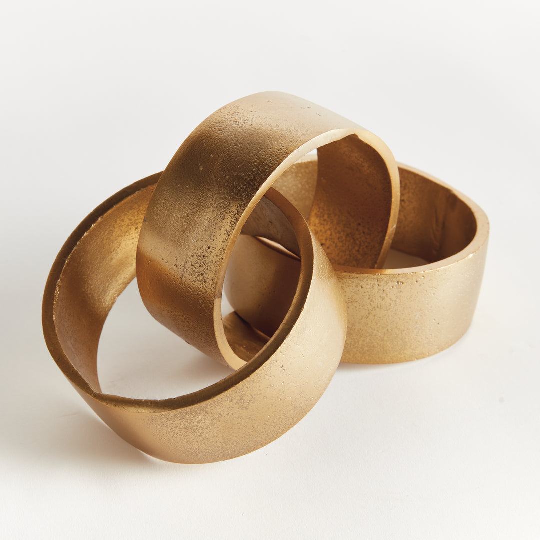 Close view of gold chain-link sculpture showing overlapping round links, textured aluminum and broad bands - Modern Organic