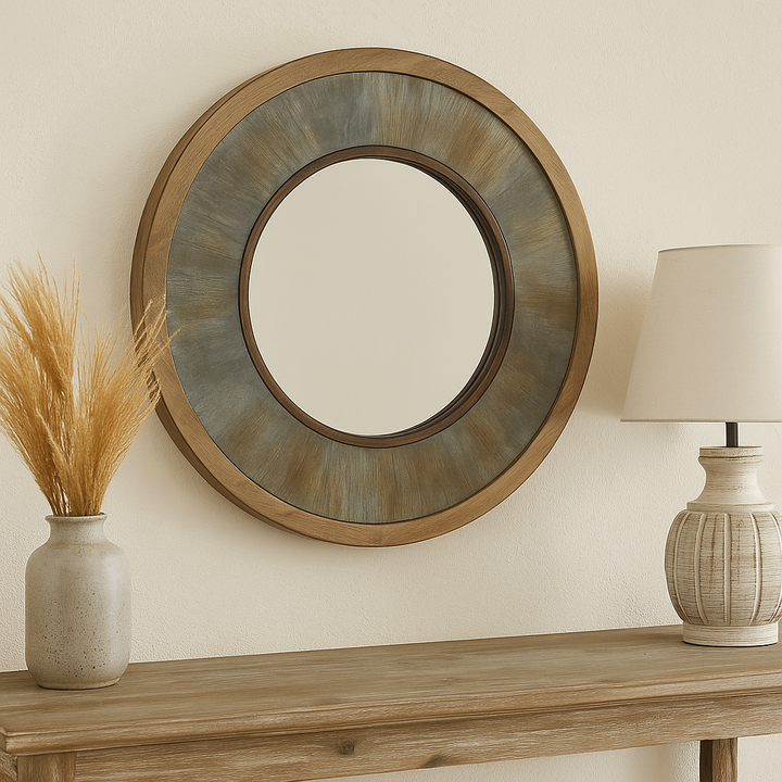 Round farmhouse mirror styled above a rustic console with dried wheat and a ceramic lamp in warm natural tones.

