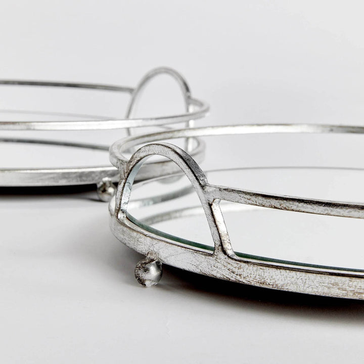 Angle detail of round mirrored trays showing antique silver finish and mirrored glass surface, modern classic styling


