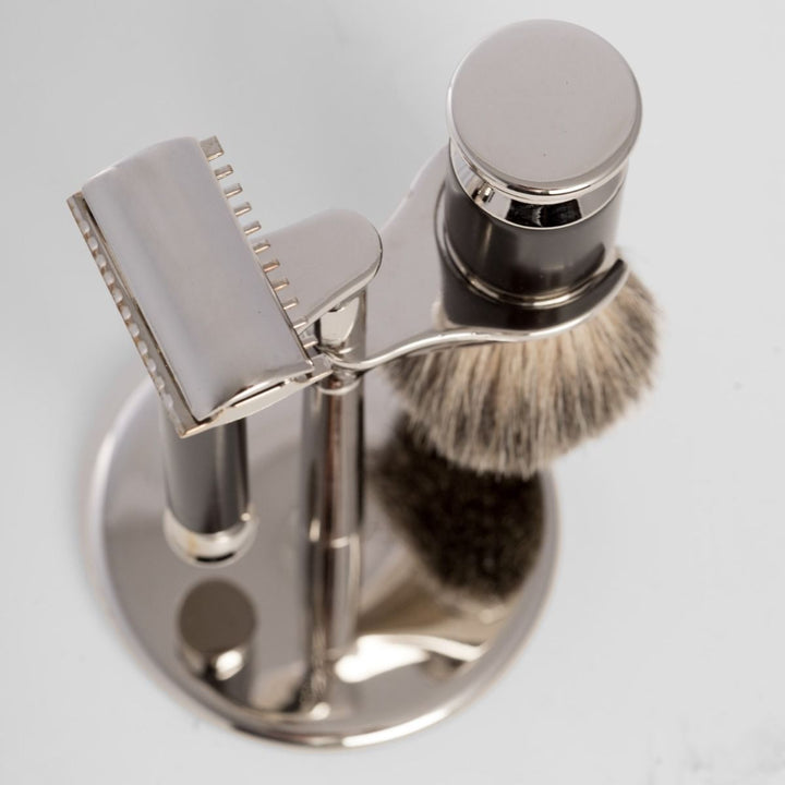 3-piece safety razor and pure badger brush shaving set with black accent handles on chrome stand, double-edge compatible.