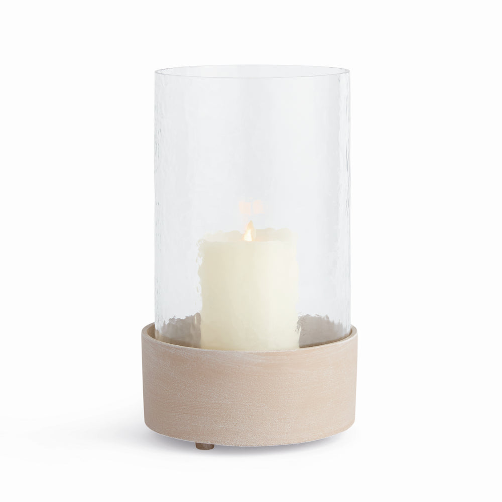 Glass cylinder hurricane candle holder with warm sandstone-look base and pillar candle on white, Modern Organic style