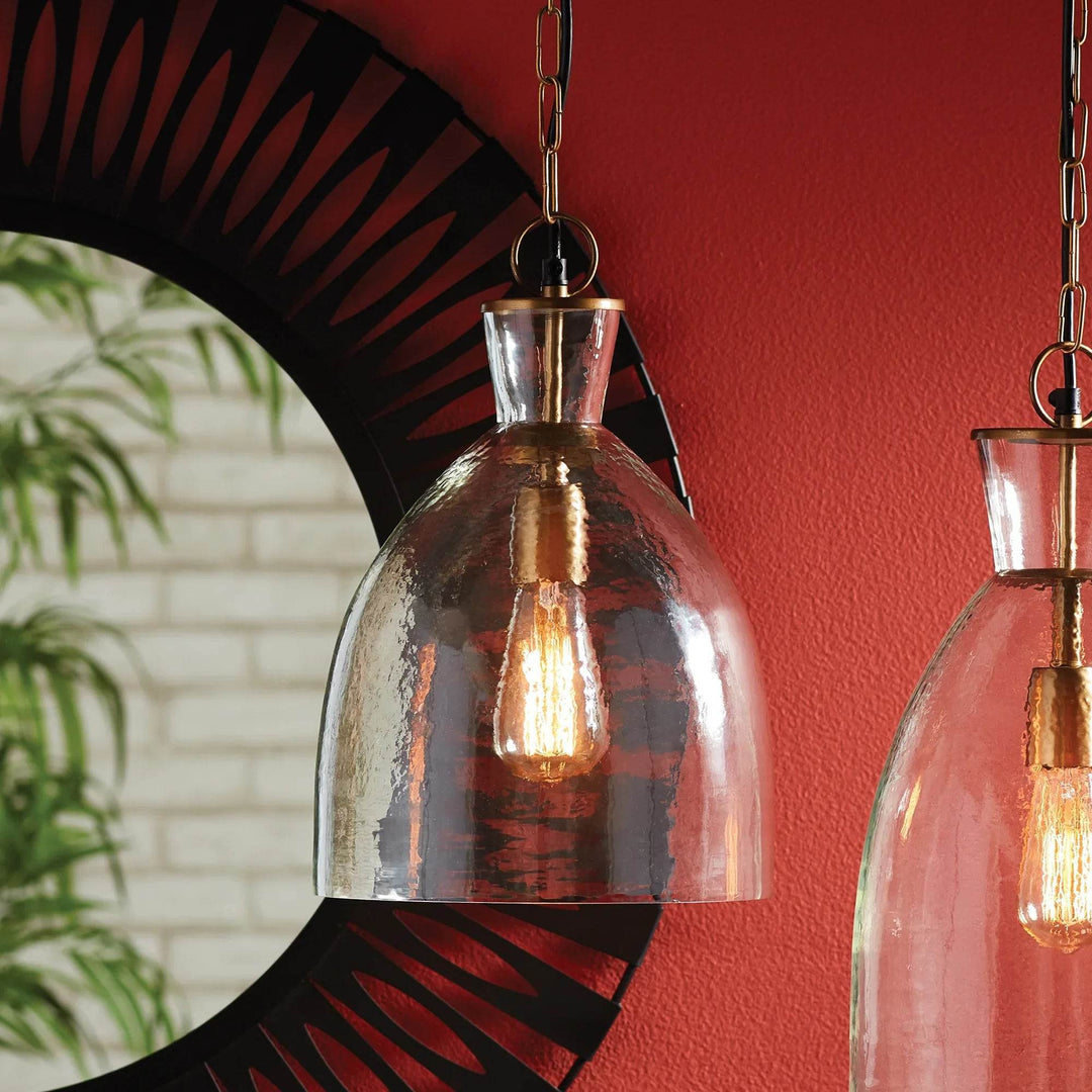 Seeded glass bell and bottle pendants with warm metal fittings, beside a round mirror and a red wall, Transitional style
