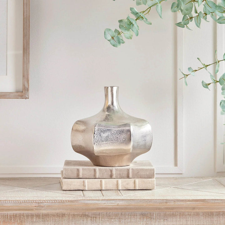 Small silver cast aluminum vase styled on books, sculptural metallic accent for console or kitchen counter

