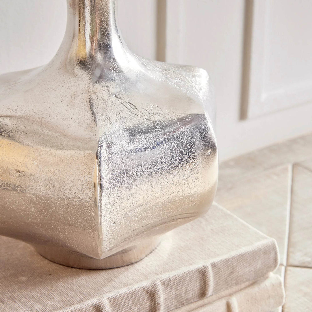 Small silver cast aluminum vase styled in a vignette with greenery, reflective metallic accent for modern coastal decor

