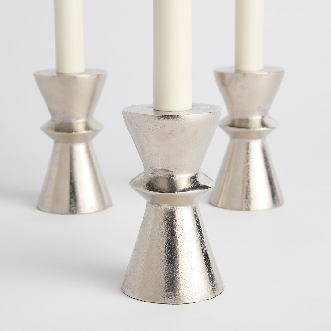 Silver aluminum taper candle holders shown angled in group of three, featuring cast hourglass silhouette and low profile – Minimalist