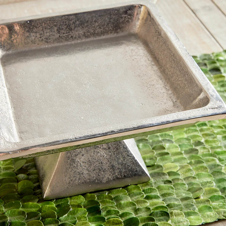 Close-up of small silver pedestal tray corner and surface texture, brushed nickel finish for transitional styling.

