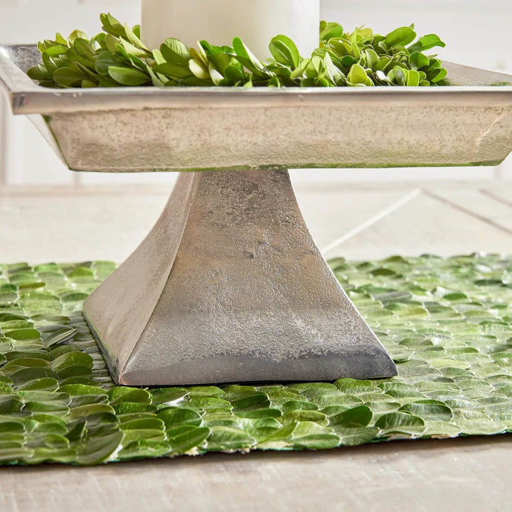Small silver pedestal tray placed on green runner, styled with greenery for modern traditional home decor.

