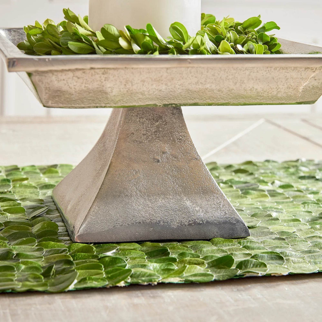 Small silver pedestal tray placed on green runner, styled with greenery for modern traditional home decor.

