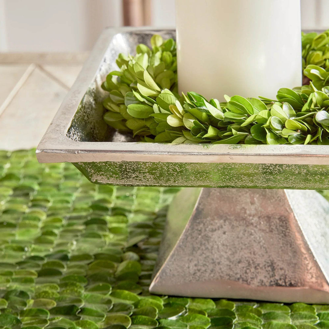 Side angle view of small brushed nickel pedestal tray, displayed with greenery for layered decorative styling.

