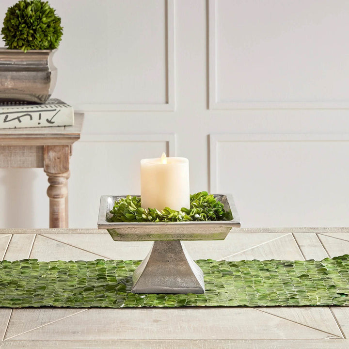 Small silver pedestal tray styled with candle and greenery, placed on table runner for seasonal or everyday decor.

