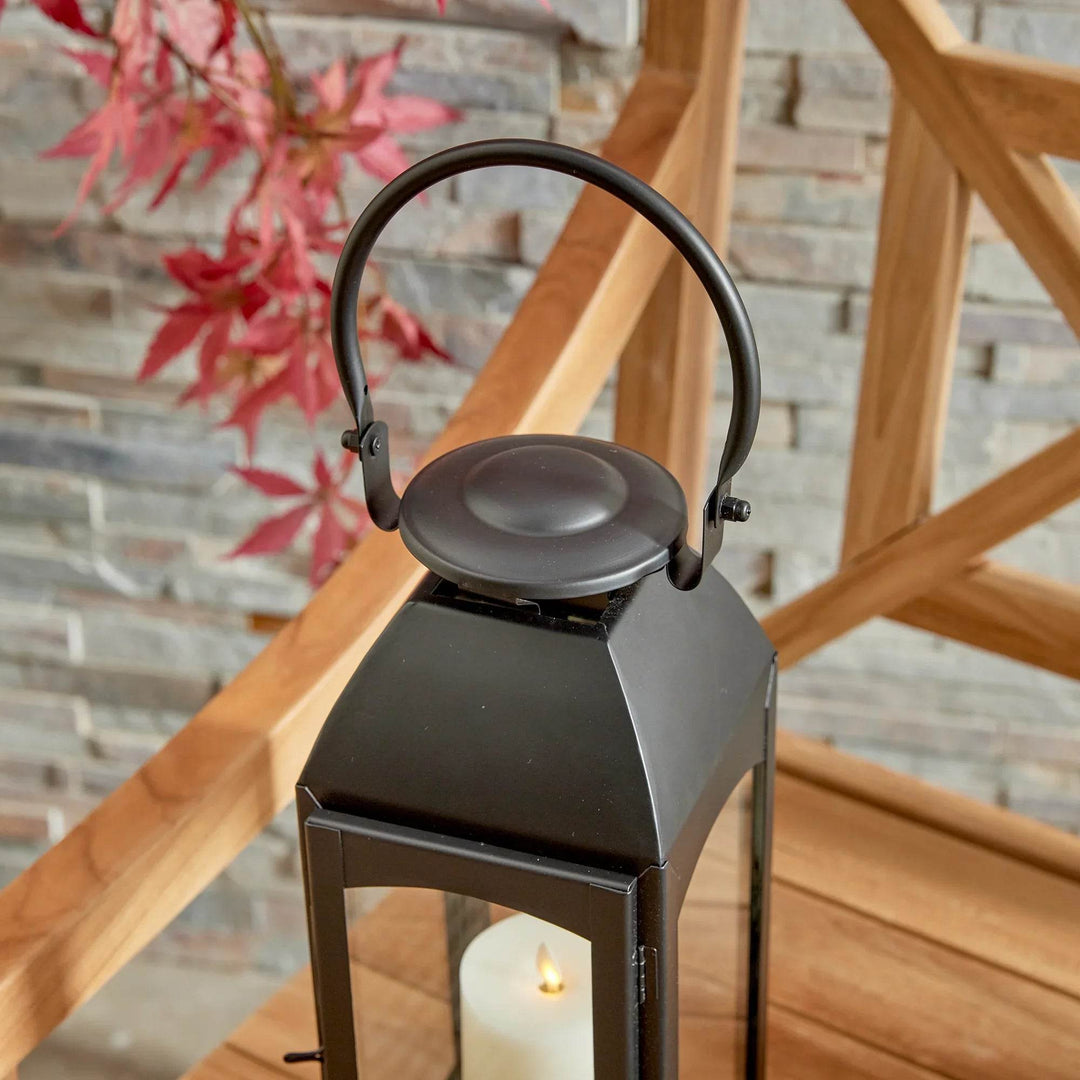 Close-up of lantern cap and ring handle resting on bench; powder-coated black finish and glass edge details highlighted – Transitional Backyard Lantern