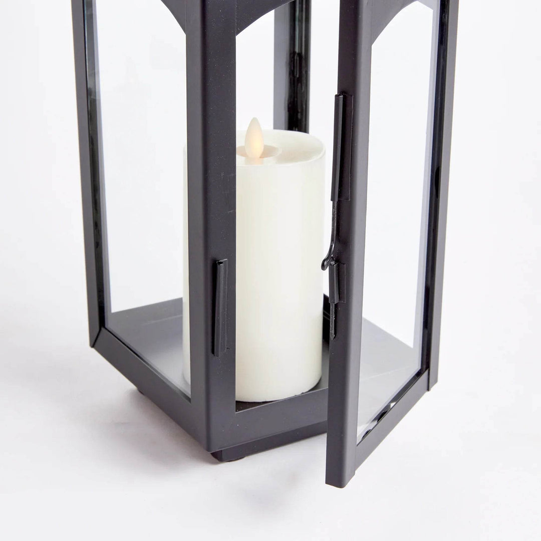 Detail of hinged door and metal latch on black lantern with glass panels; pillar candle inside on metal base, studio view – Transitional Styling