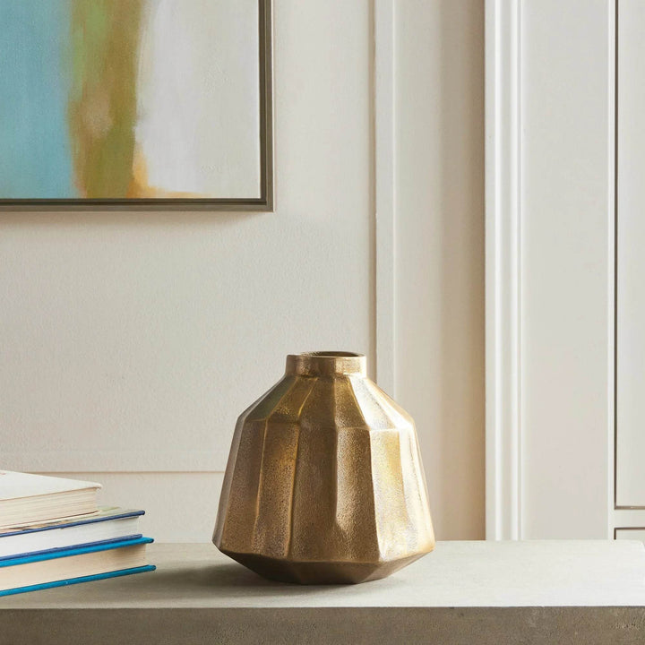 Small brass decorative vase with faceted profile styled on shelf near books, warm antique finish accent for home decor – Contemporary Classic.

