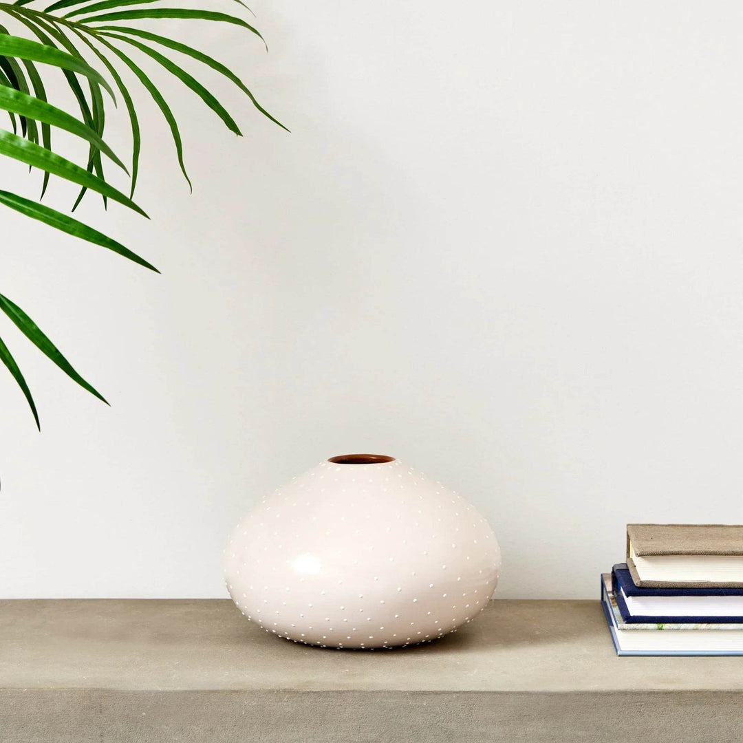 Small off-white ceramic vase styled on shelf beside stacked books and palm leaf – Modern Organic

