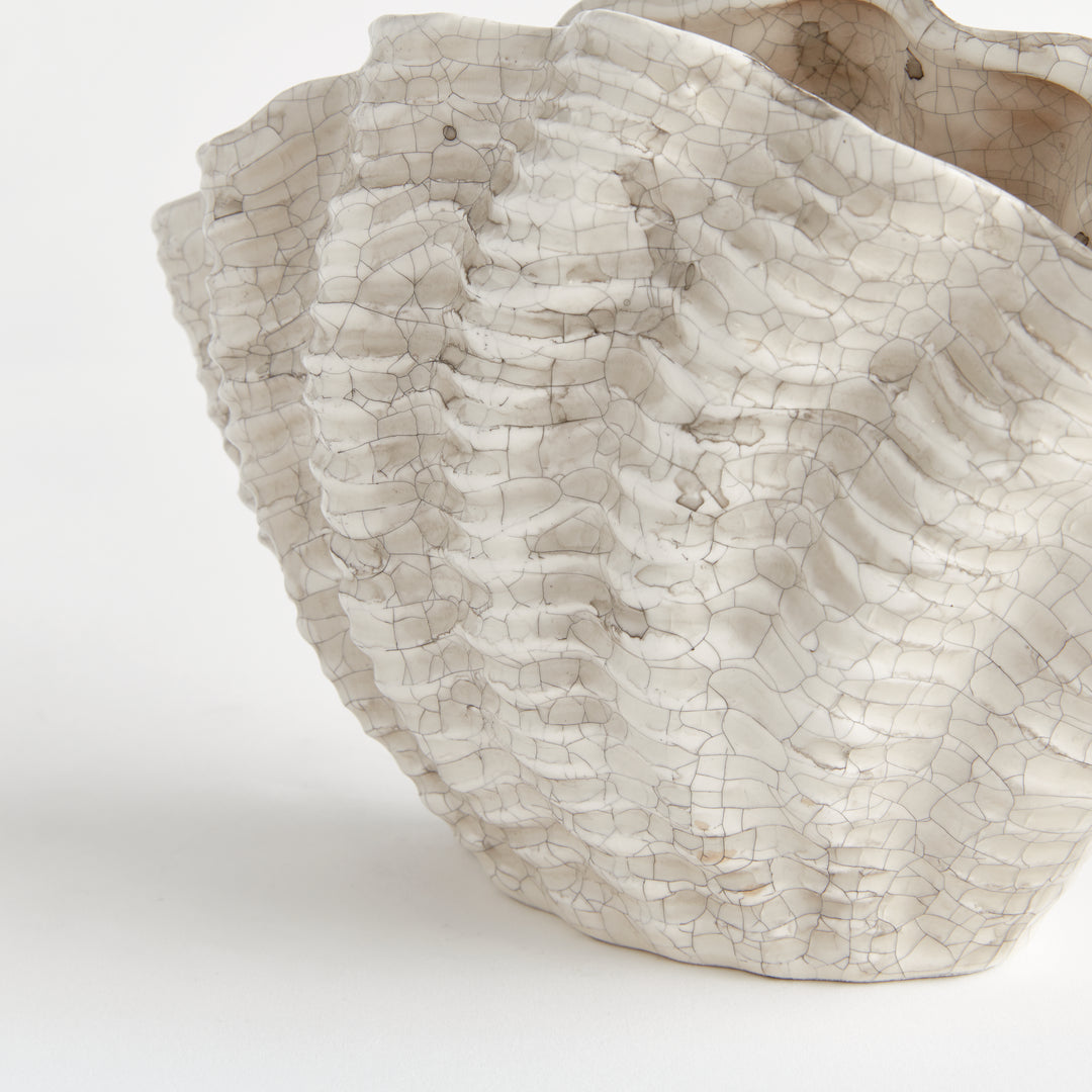 Close view of the cream crackle glaze and layered shell texture on a small clay vase against white, Coastal Transitional