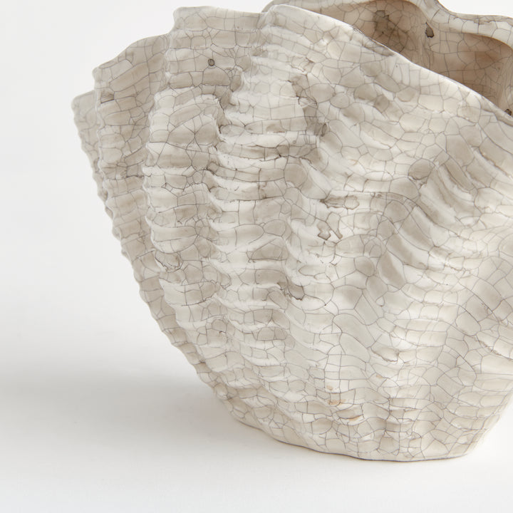 Close view of the cream crackle glaze and layered shell texture on a small clay vase against white, Coastal Transitional