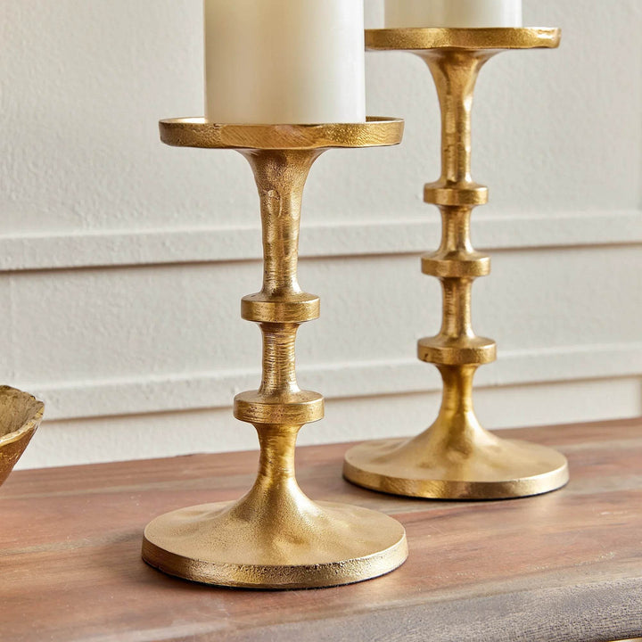 Close-up of round base of small gold candle holder showing burnished metallic finish and sturdy construction