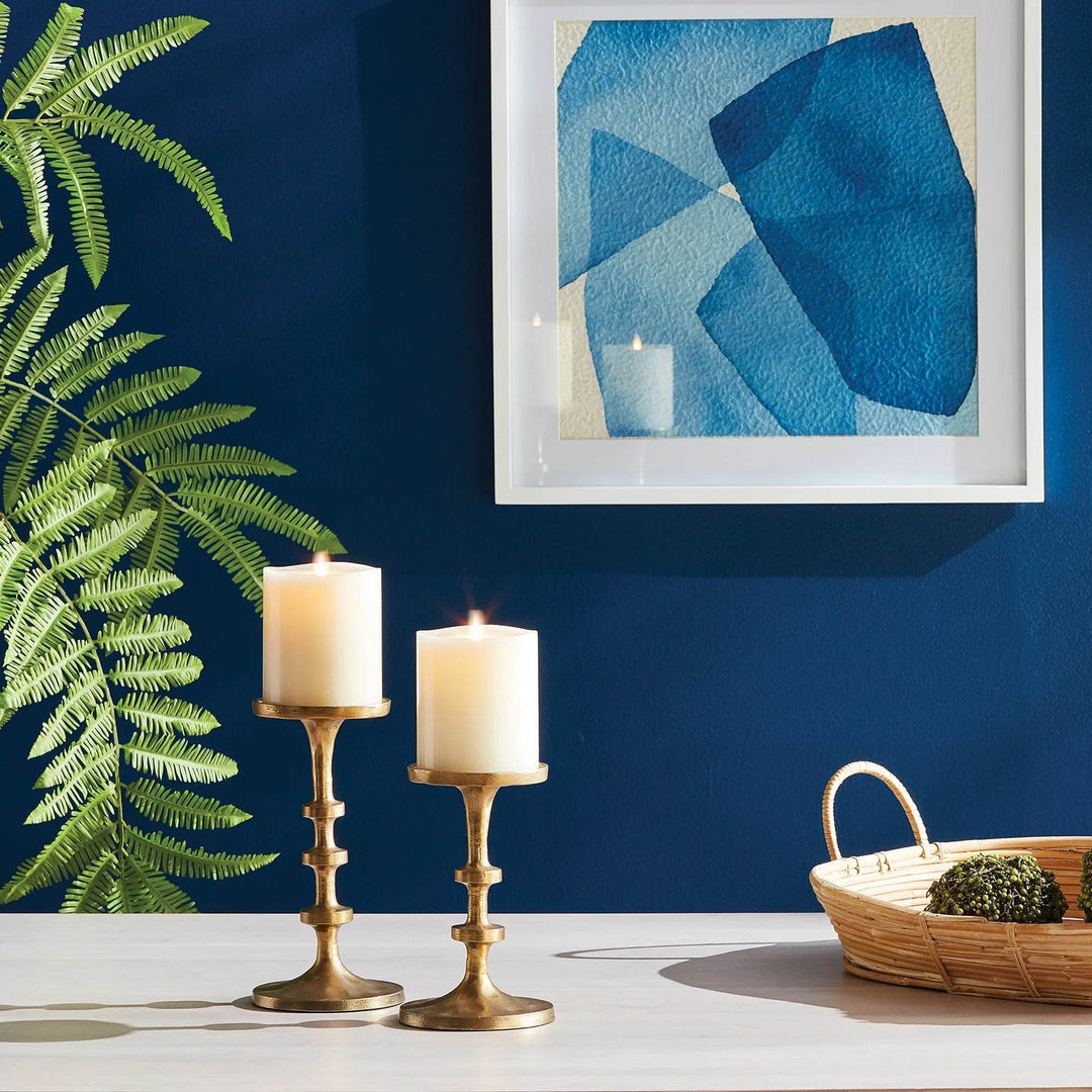 Small modern gold candle holders set of 2 displayed on table with blue accent wall and framed abstract artwork